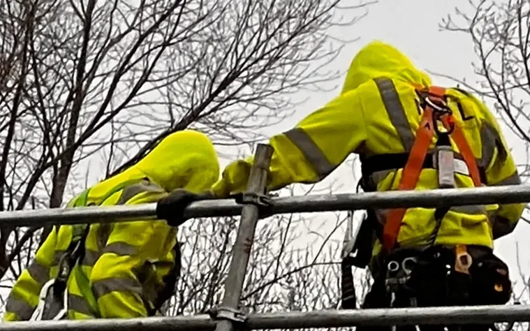 Two TMP team members handling scaffold components